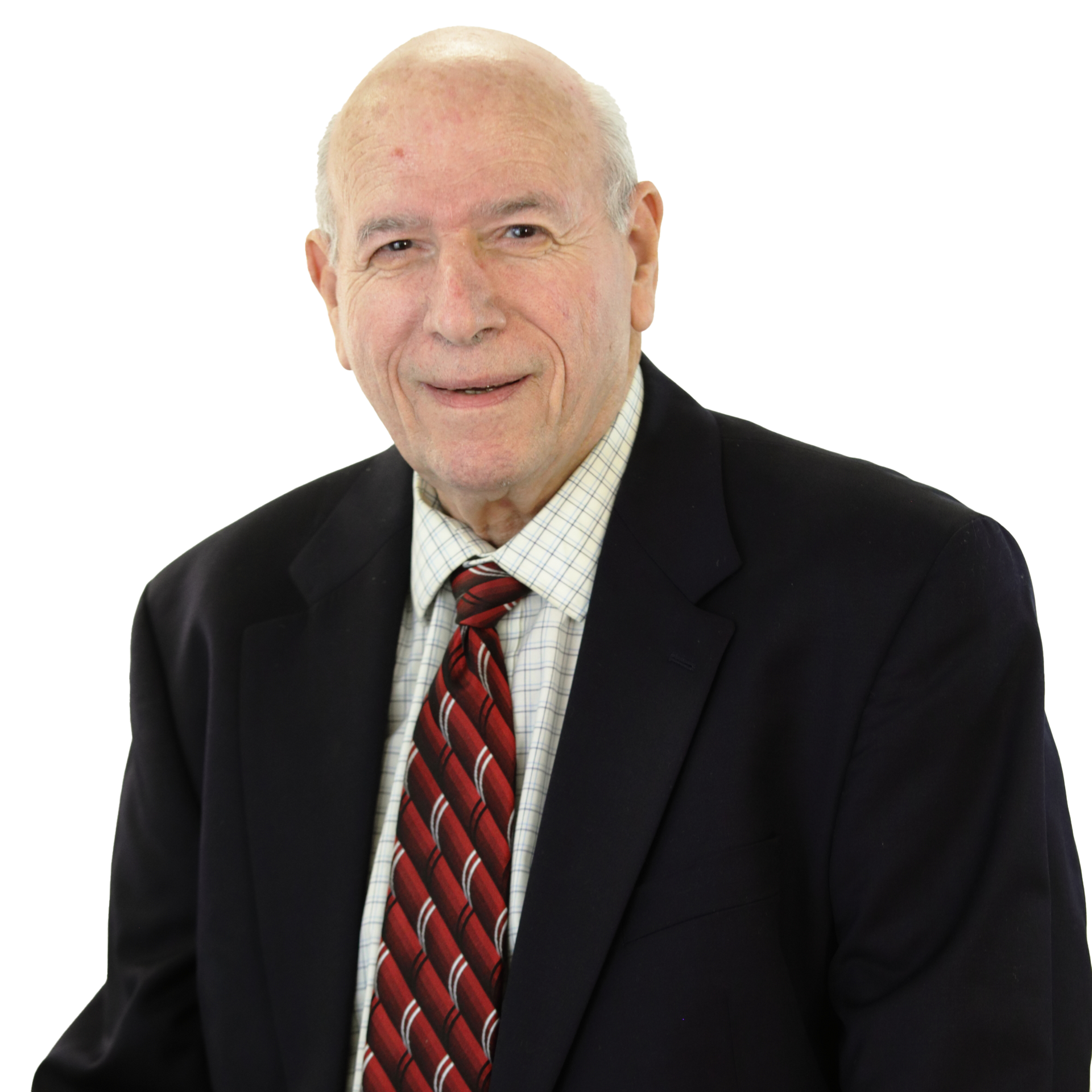 Older man with a bald head, in a dark suit, red tie, and a patterned shirt, smiling.