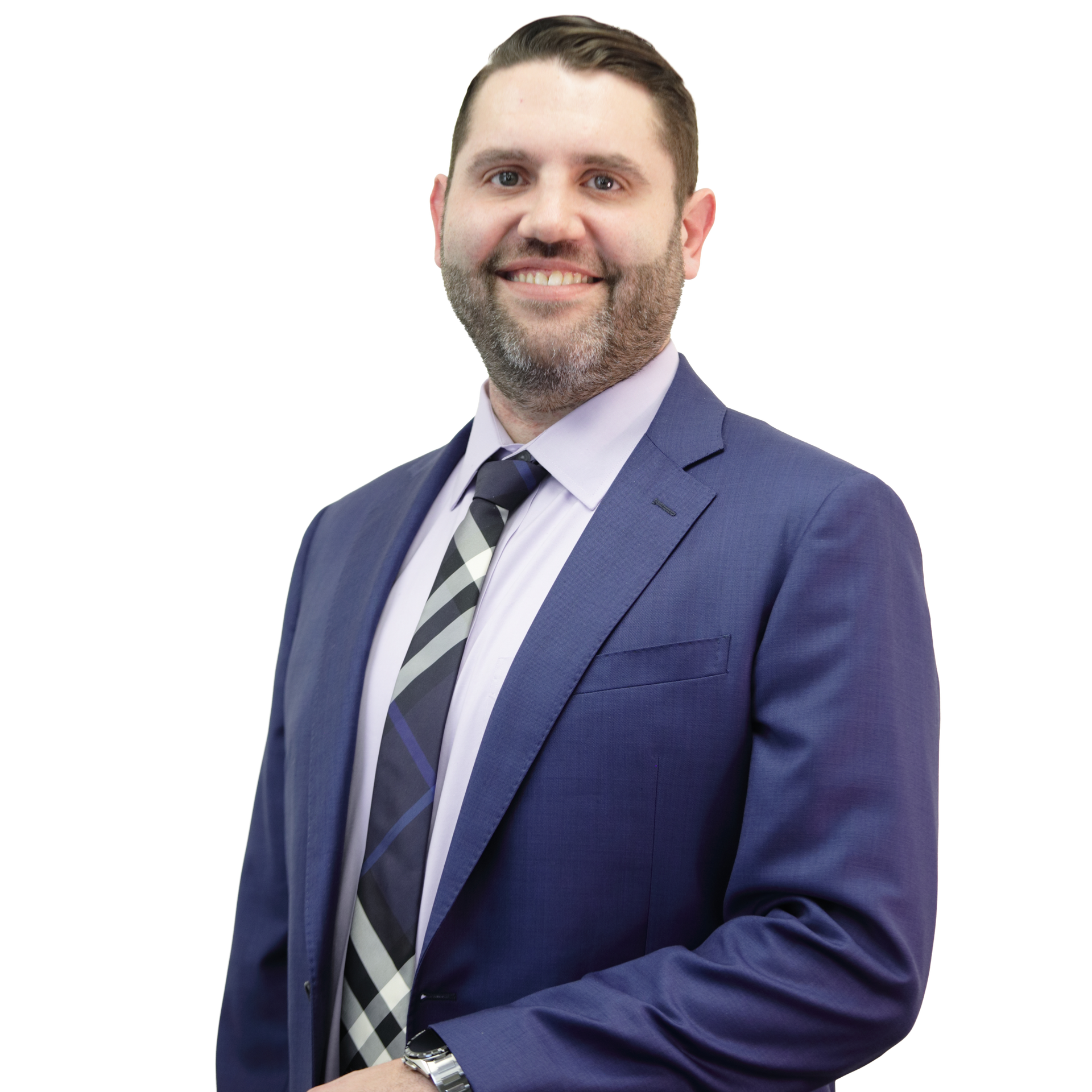 Man with beard smiles, wearing a blue shirt under a gray suit jacket against a white background.