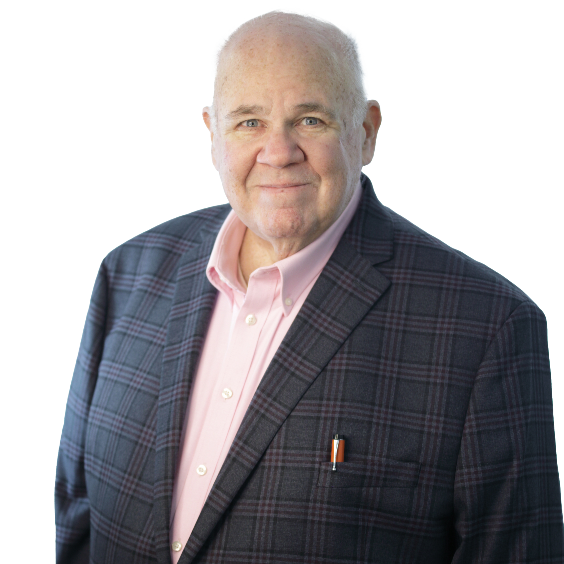 Man in plaid jacket and pink shirt, smiling. A pen is in his pocket.