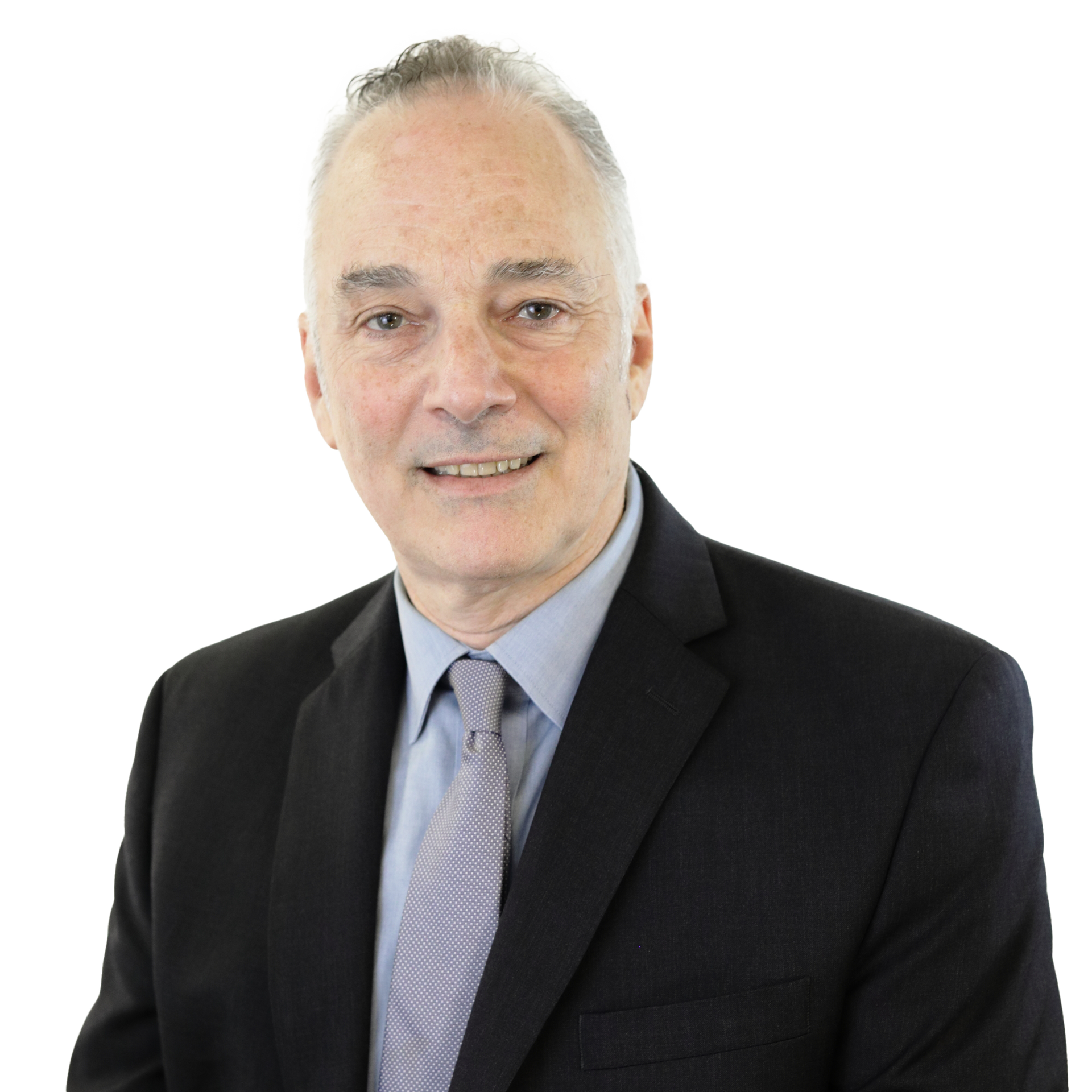 Man in a dark suit and light blue tie smiling at the camera against a white background.