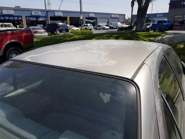 White car parked in a lot with storefronts and other vehicles in the background