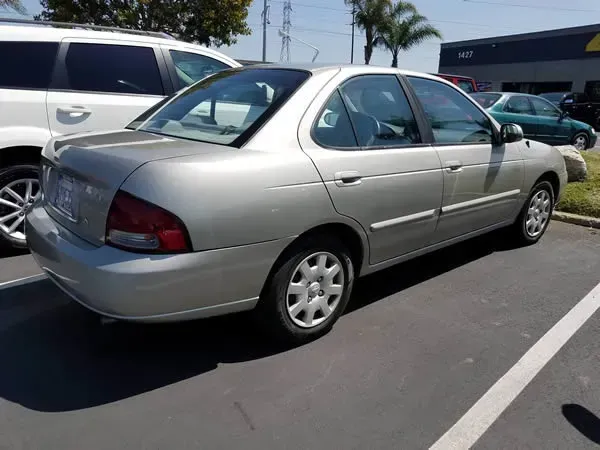 Silver sedan parked in a lot beside a white SUV, with palm trees in the background.