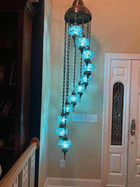 A spiraling Turkish mosaic pendant lamp with blue-lit globes hangs in a foyer.