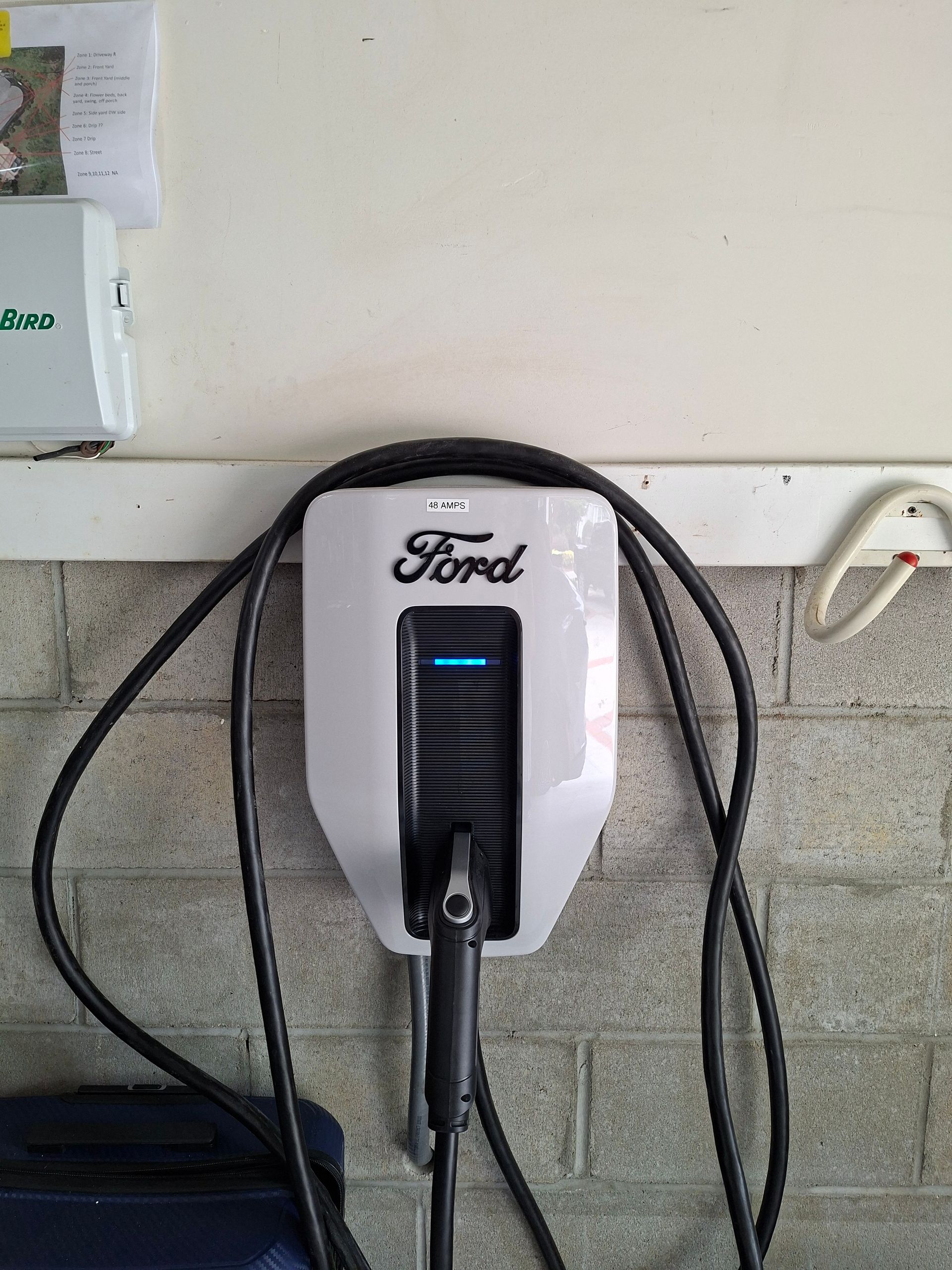 Ford electric vehicle charging station mounted on a wall with a plugged-in cable.