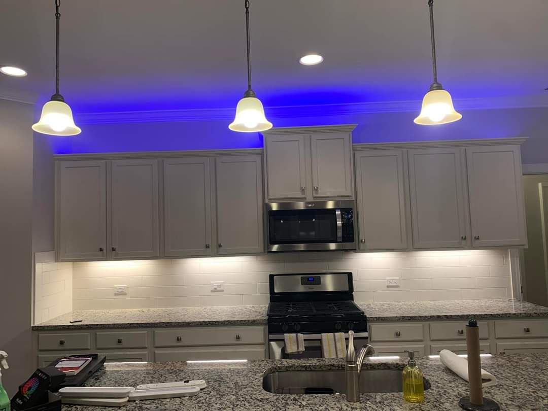 Kitchen with white cabinets, blue and white lighting, and stainless steel appliances.