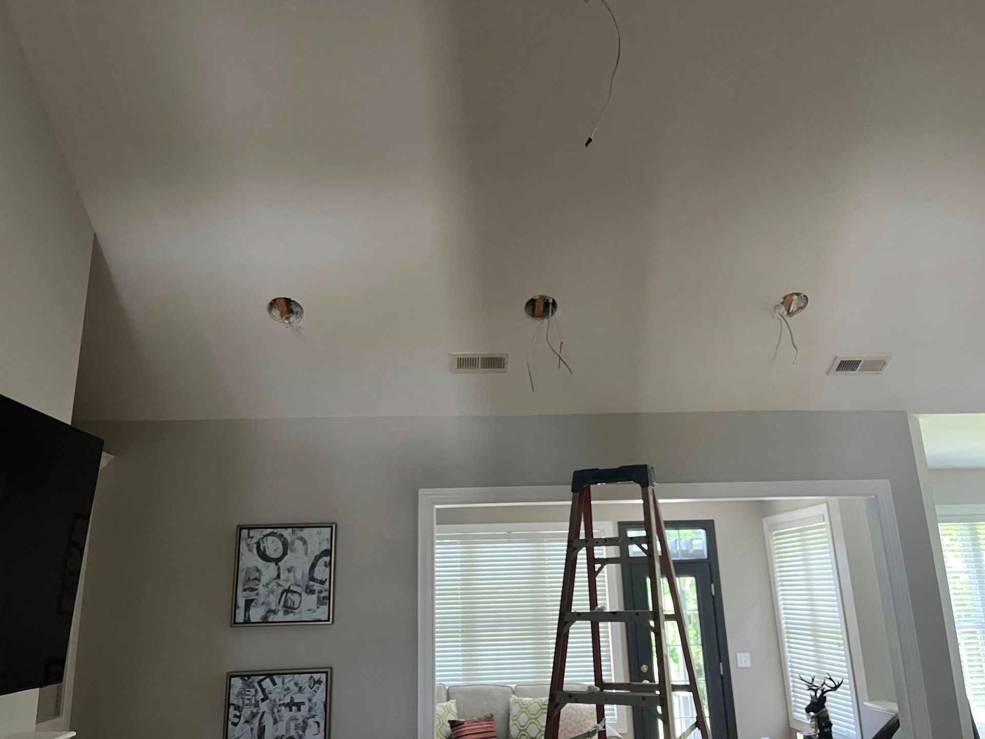 Ceiling with three recessed light fixtures, exposed wires, and a ladder.