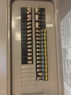 Electrical panel with rows of black and yellow circuit breakers.