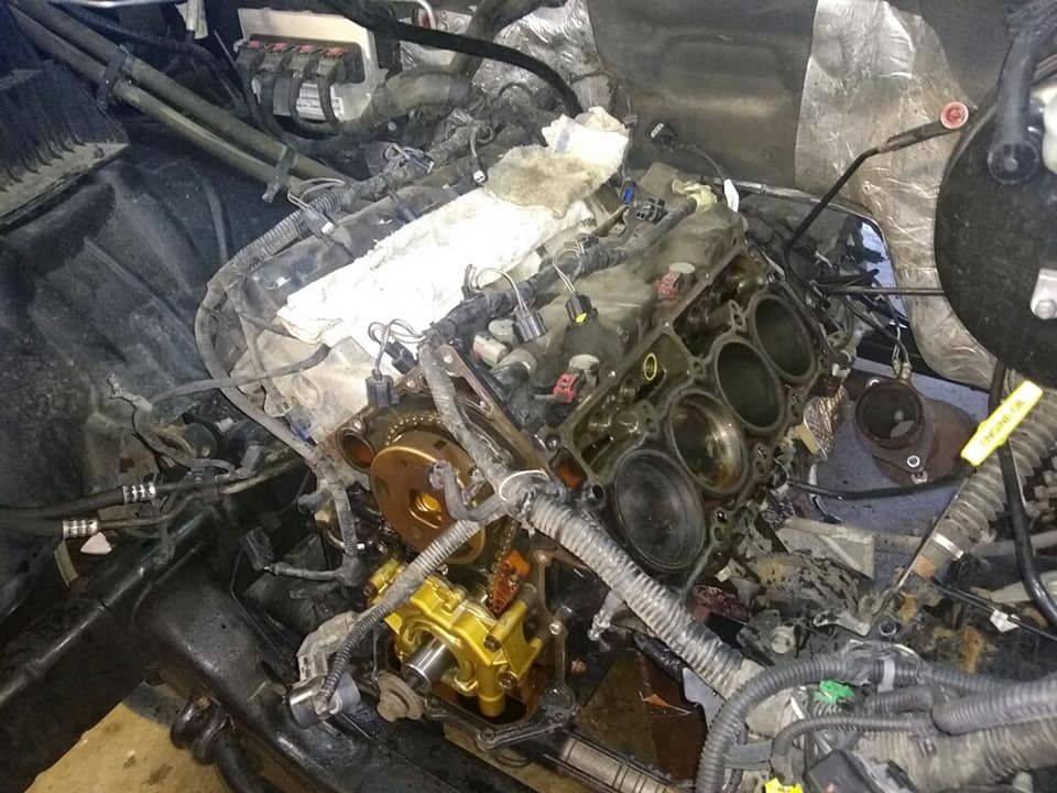 Engine block partially disassembled, oil-stained, inside a vehicle's engine bay.