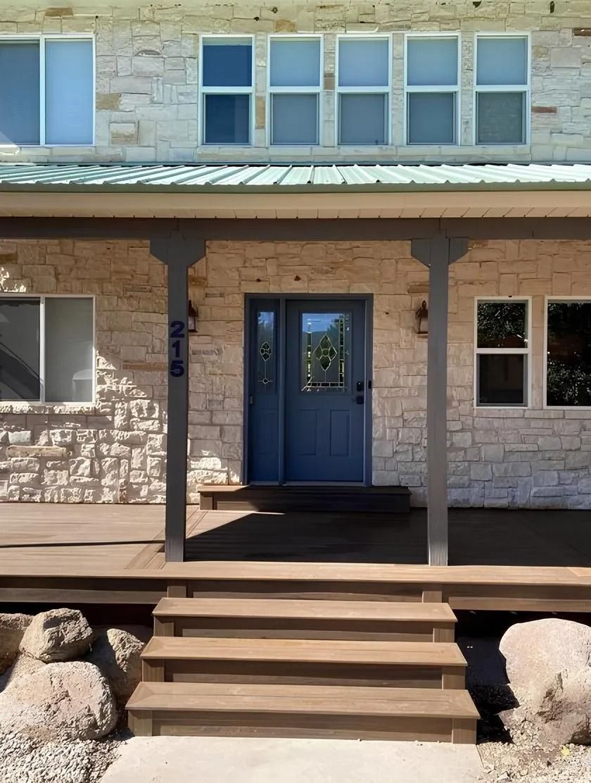 Stone house with blue door and porch, dark brown steps.