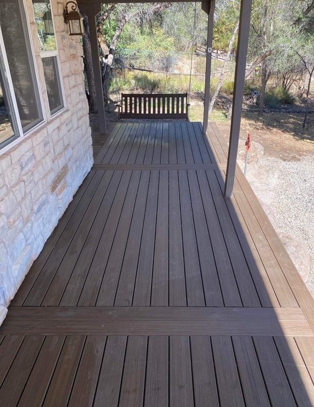 Covered porch with composite decking, swing, and stone wall.