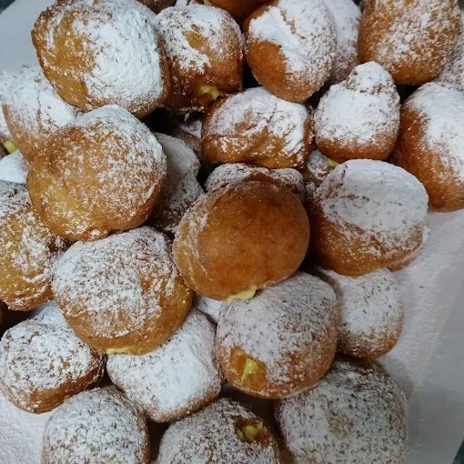 Una pila di bignè dorati spolverati di zucchero a velo.