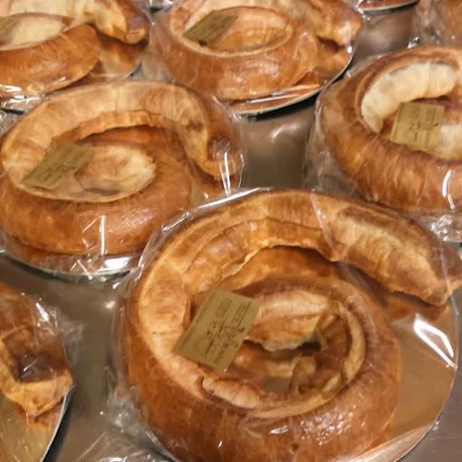 Diversi pasticcini a forma di spirale avvolti nella plastica, esposti su un bancone.