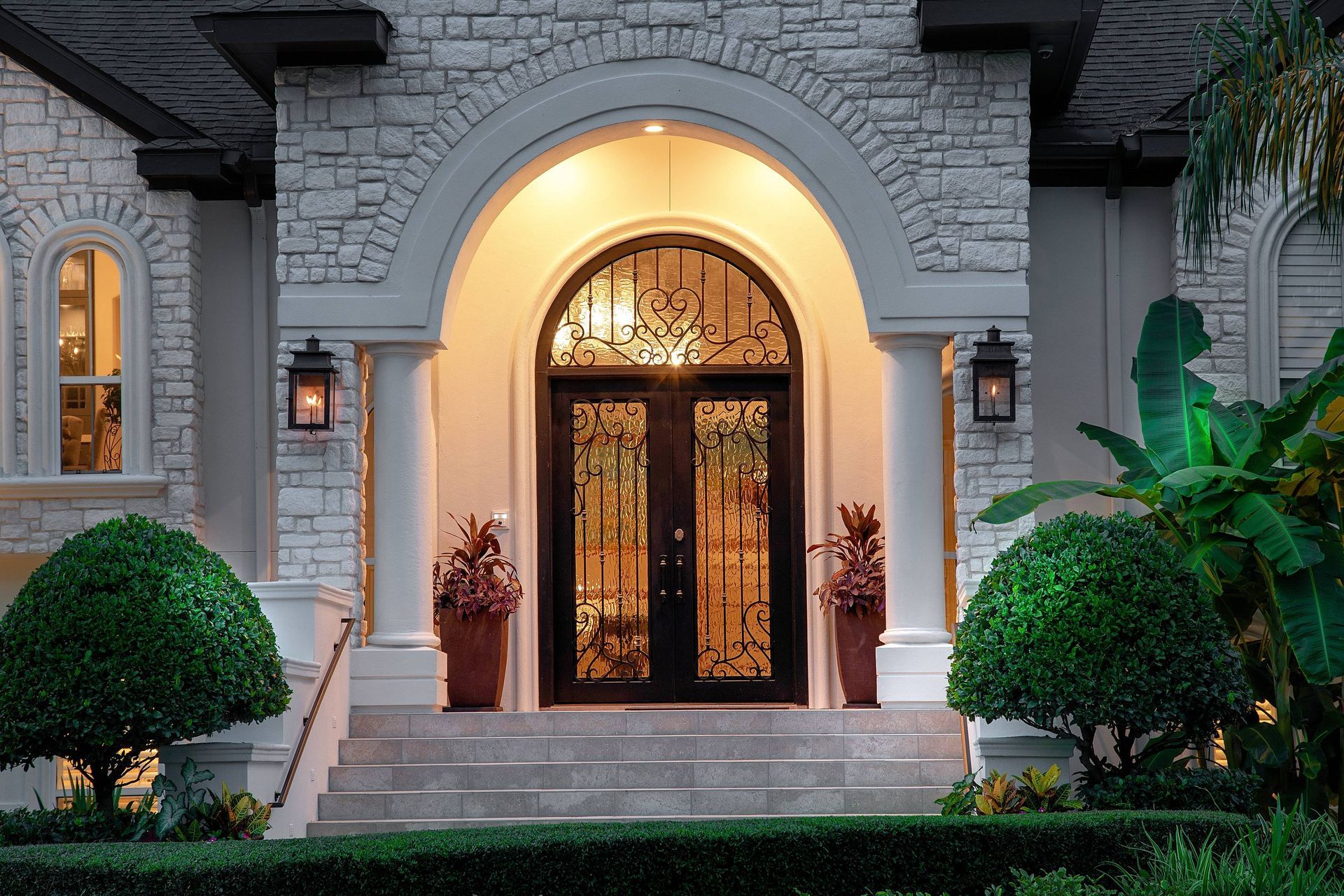 A large white brick house with a large arched door