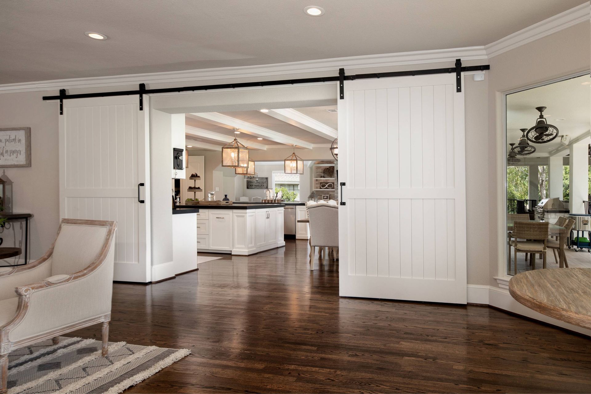 A living room with sliding barn doors leading to a kitchen and dining room.