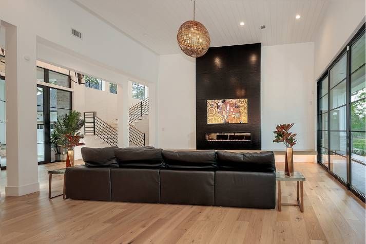 A living room with a black couch and a fireplace.