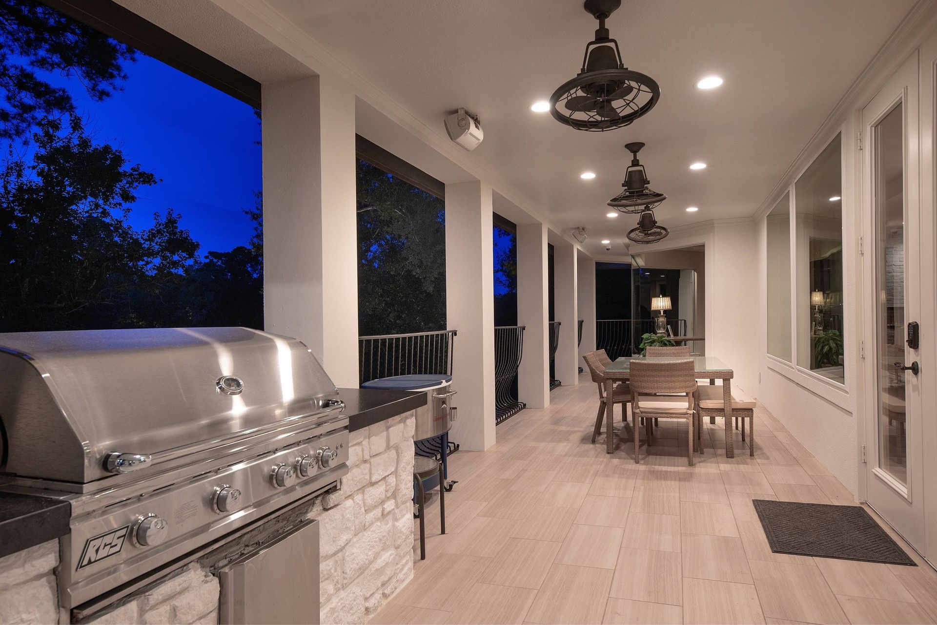 A large porch with a grill and a dining table.