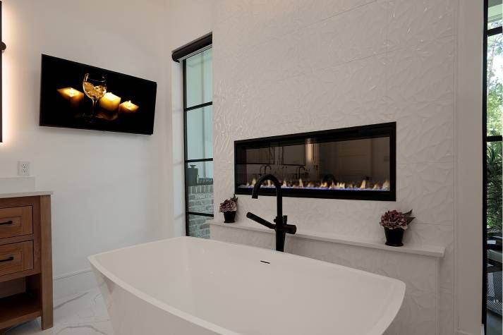 A bathroom with a bathtub and a fireplace in the wall.