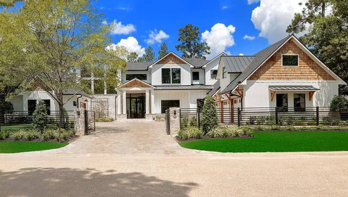 A large white house with a driveway and a fence in front of it.