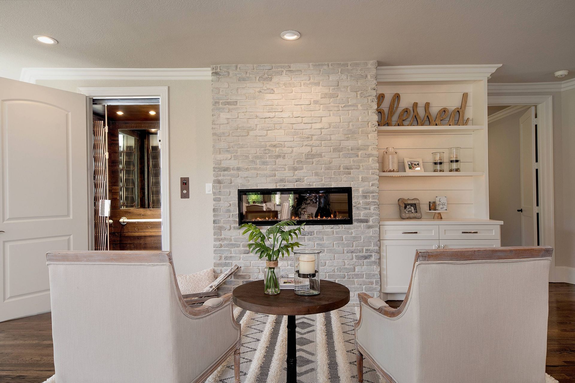 A living room with two chairs , a table and a fireplace.