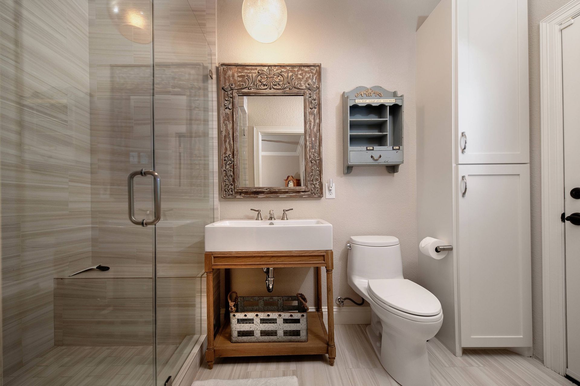 A bathroom with a toilet , sink , mirror and walk in shower.