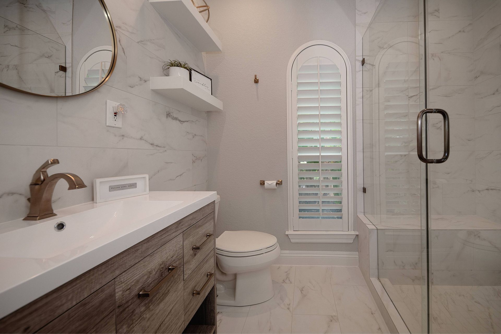 A bathroom with a toilet , sink , mirror and walk in shower.