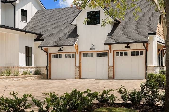 A large white house with three garage doors and a driveway.