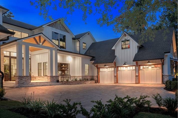 A large white house with three garage doors is lit up at night.