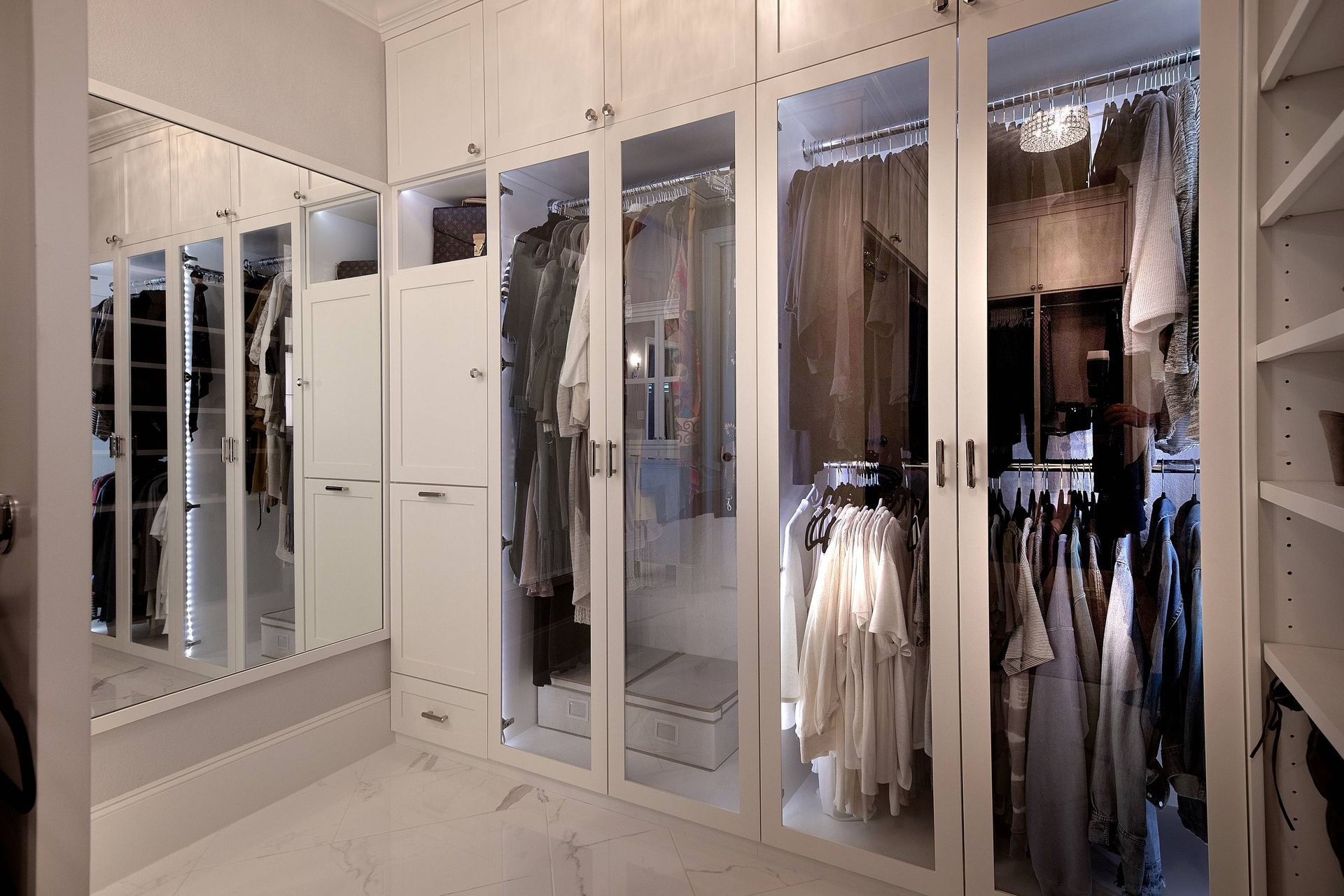 A walk in closet filled with lots of clothes and a mirror.
