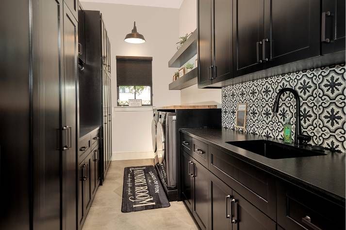 A kitchen with black cabinets , a sink , and a window.