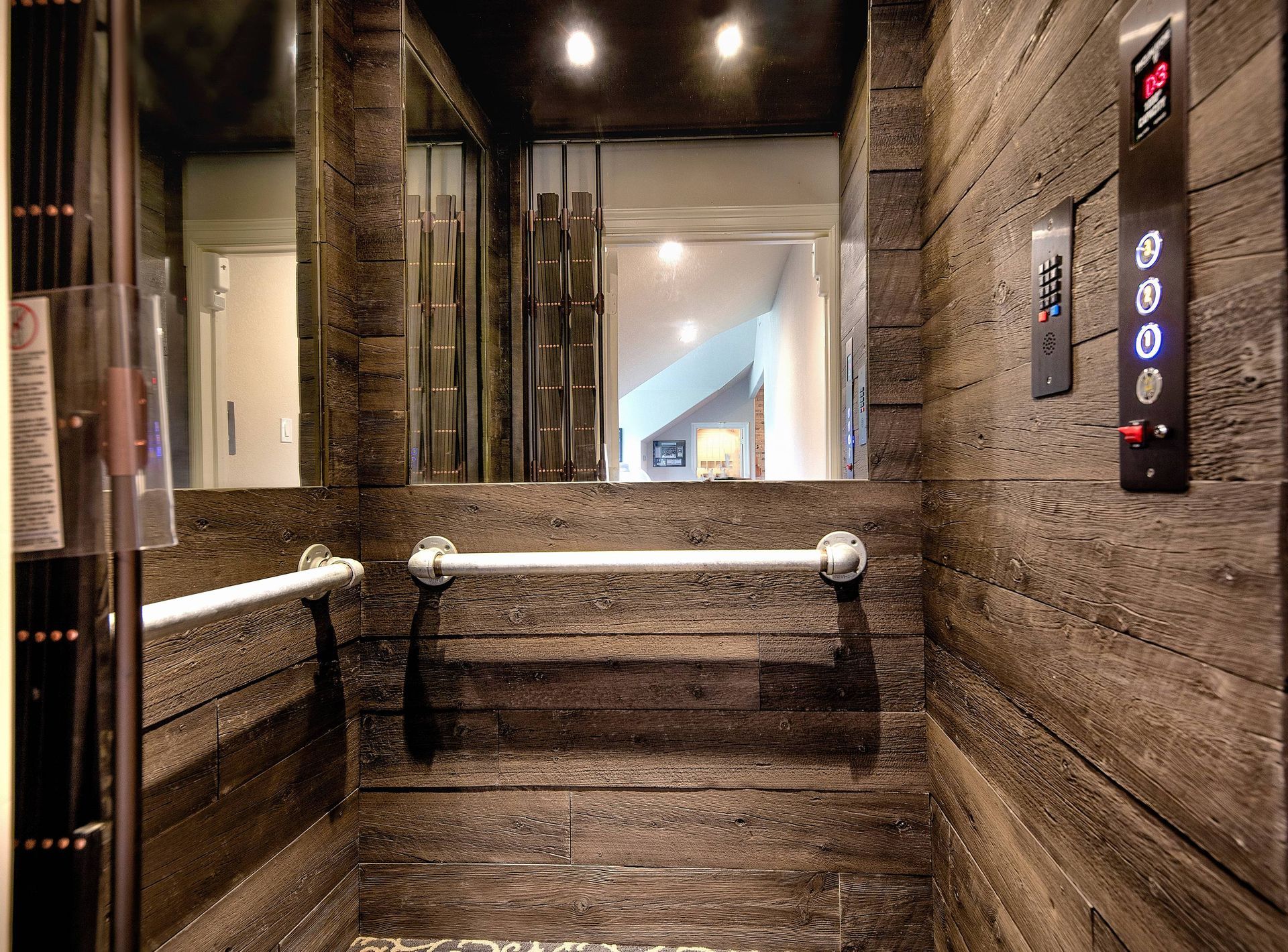 A wooden elevator with a hand rail and a mirror.