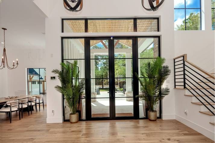 A large room with a lot of windows and plants in pots.