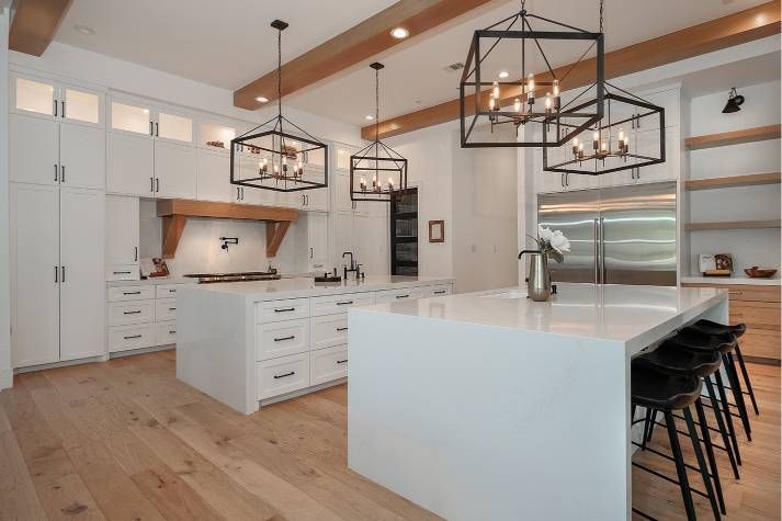 A kitchen with white cabinets , hardwood floors , stainless steel appliances and a large island.