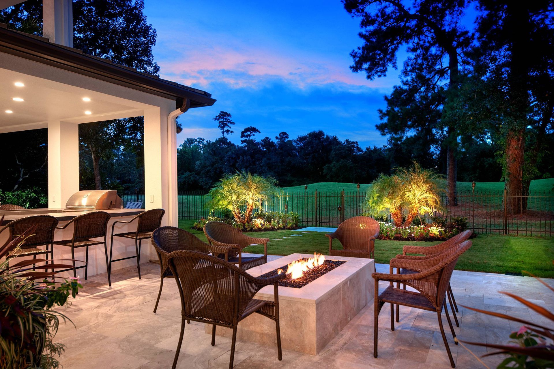 A patio with a fire pit and chairs at night