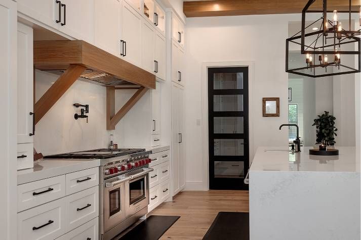 A kitchen with white cabinets , stainless steel appliances , and a black door.