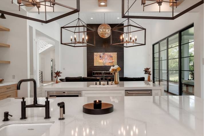A kitchen with white counter tops , a sink , and a dining room in the background.