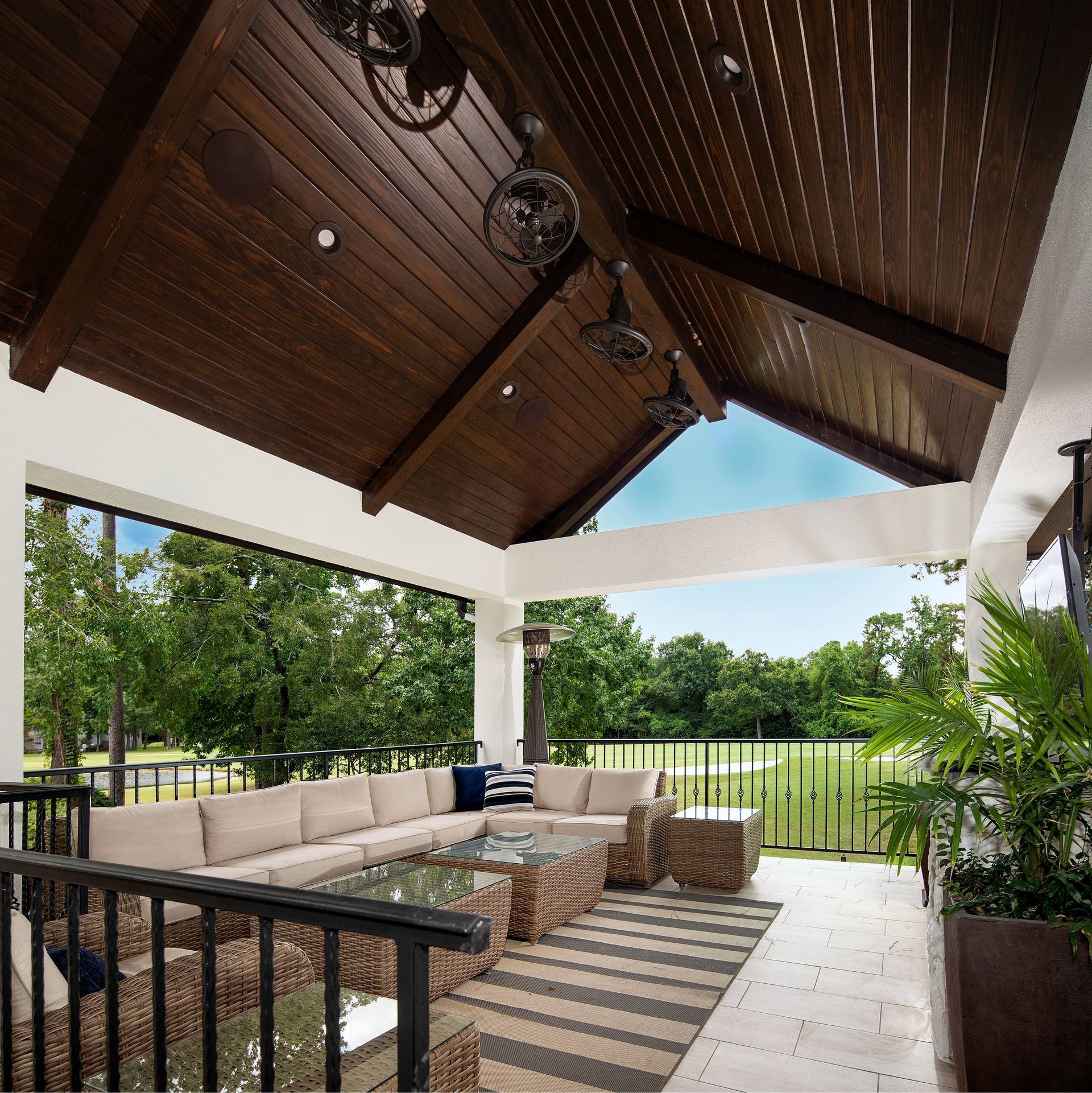 A patio with a couch and a rug under a wooden ceiling