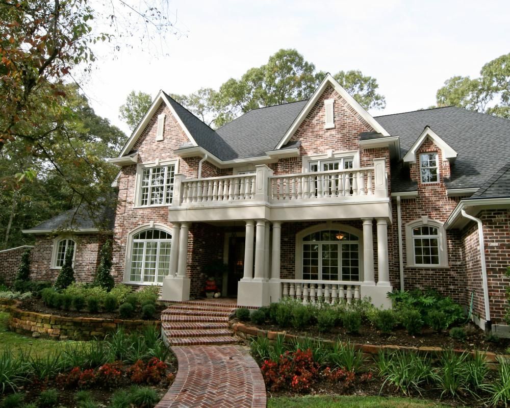 A large brick house with a brick walkway leading to it