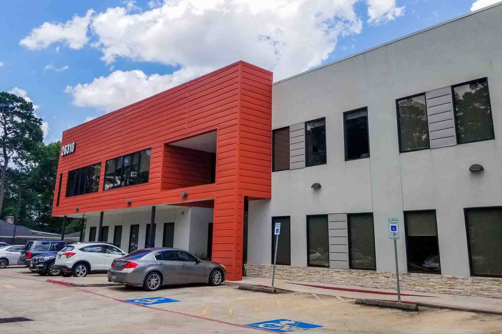 A large orange and white building with cars parked in front of it.