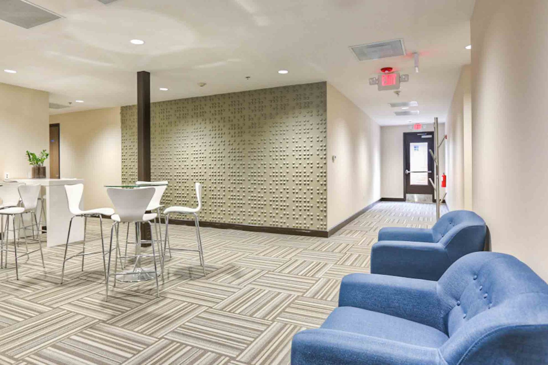 A hallway with blue chairs and tables in a building.