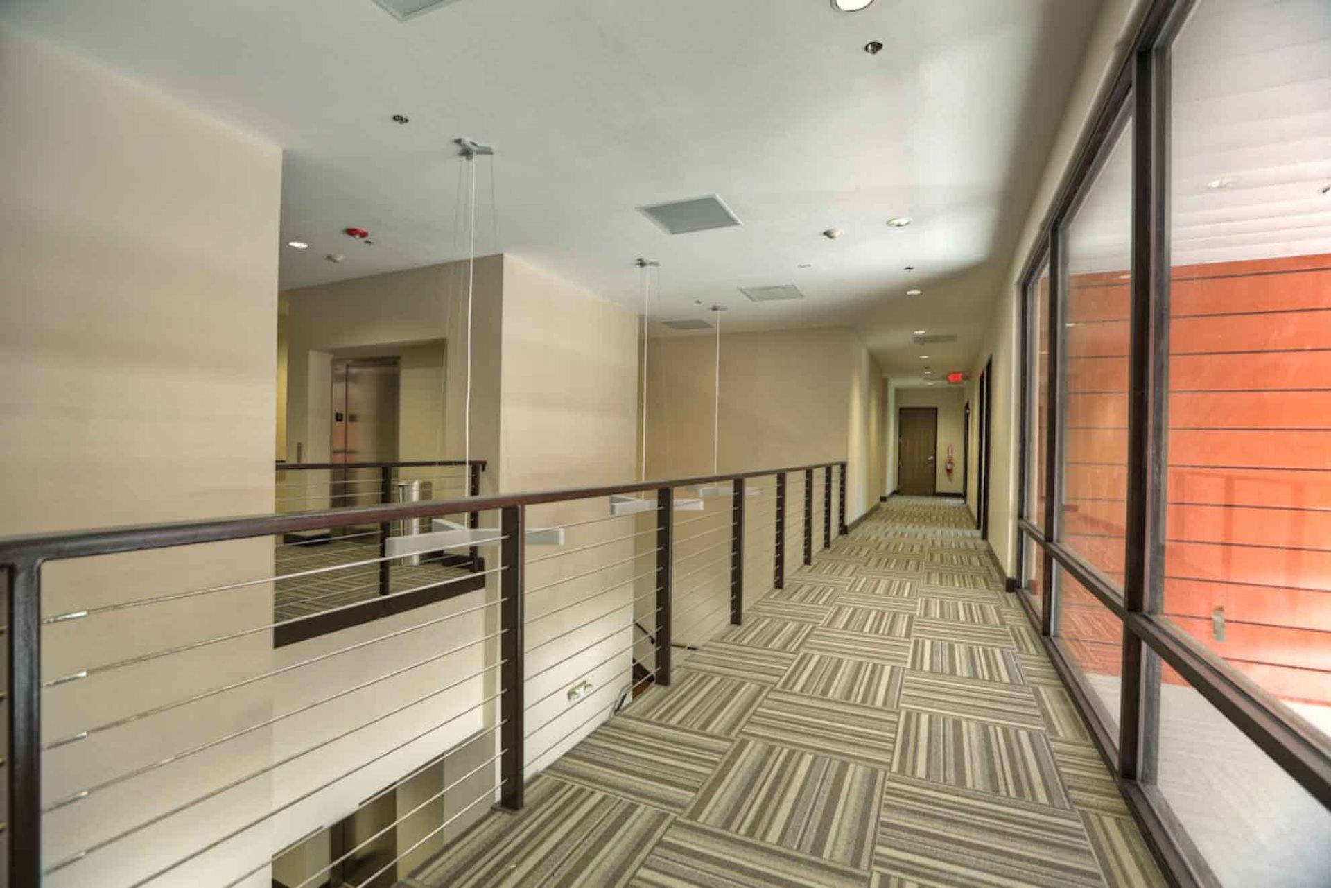 A long hallway with a railing and a lot of windows