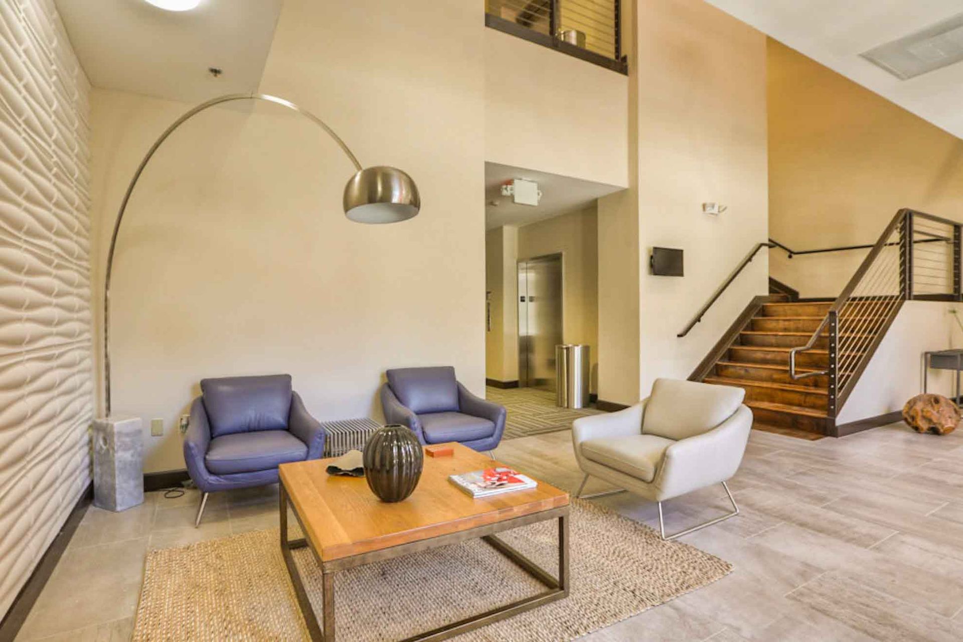 A living room with two chairs , a coffee table , and stairs.