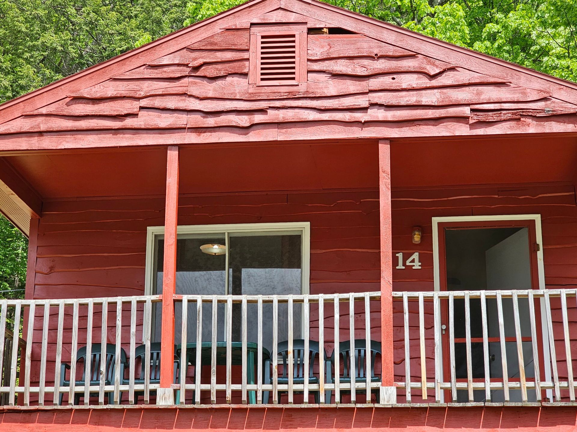 Red wooden house porch with white railing and front door number 14