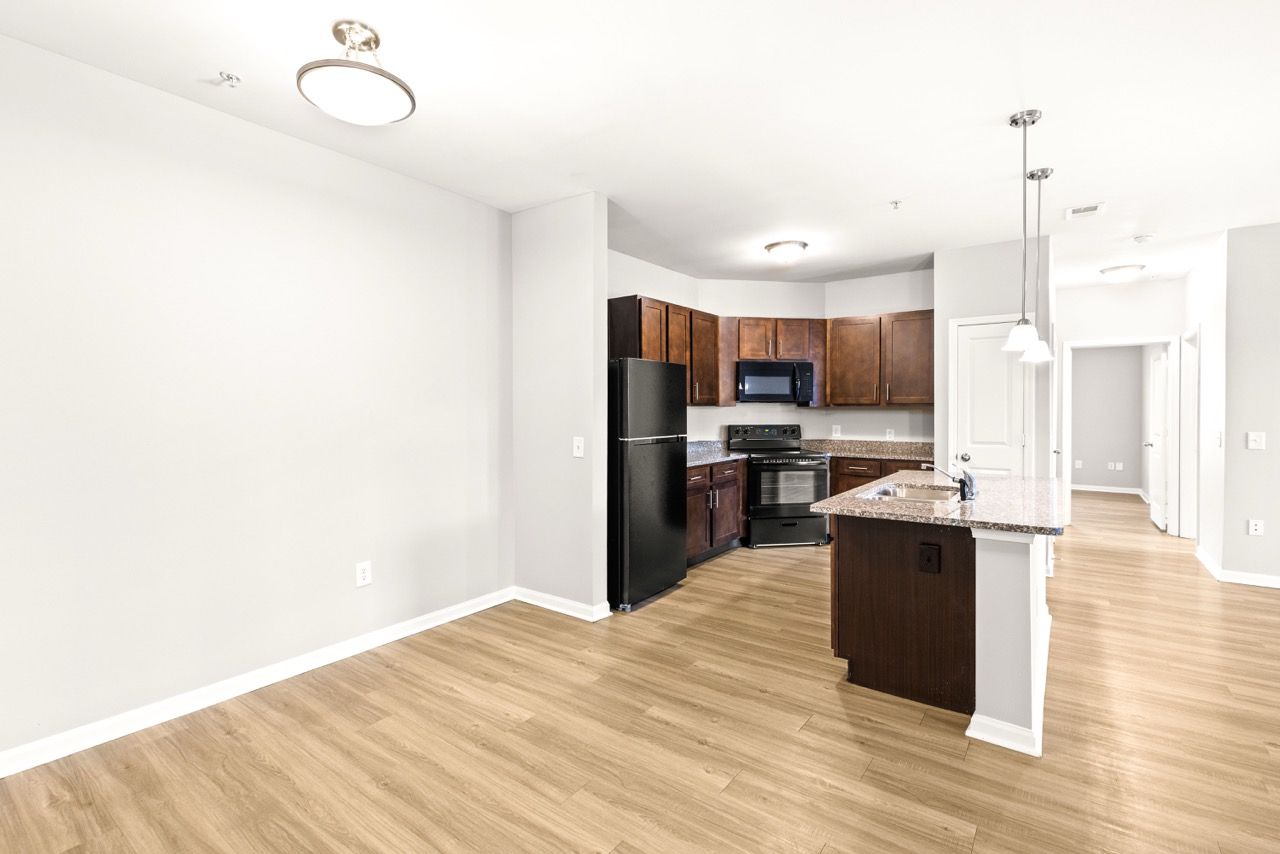 Open-concept kitchen area with granite island, dark wood cabinets, and black appliances.