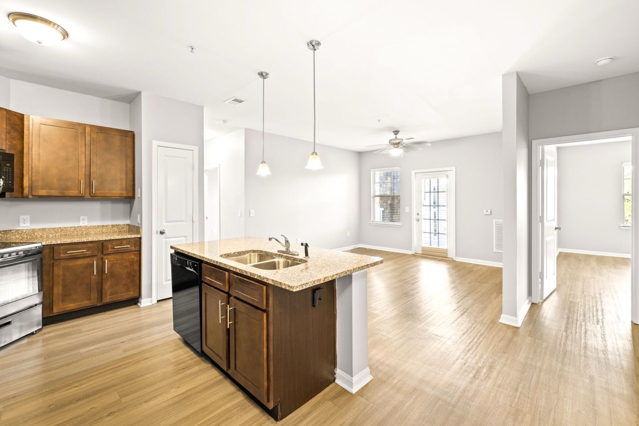 Open-concept kitchen with granite island, wood cabinets, and stainless appliances.
