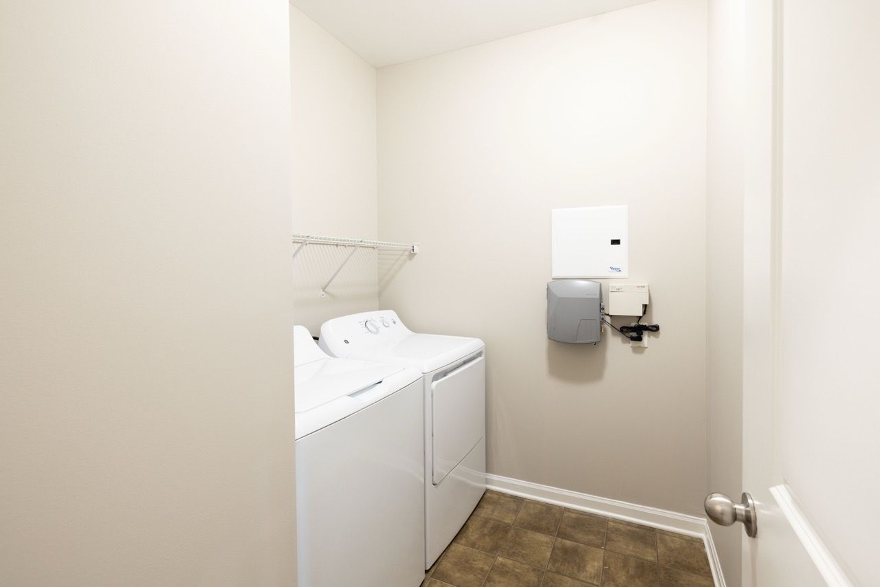 Laundry closet with a washer and dryer, a shelf, and a utility panel.