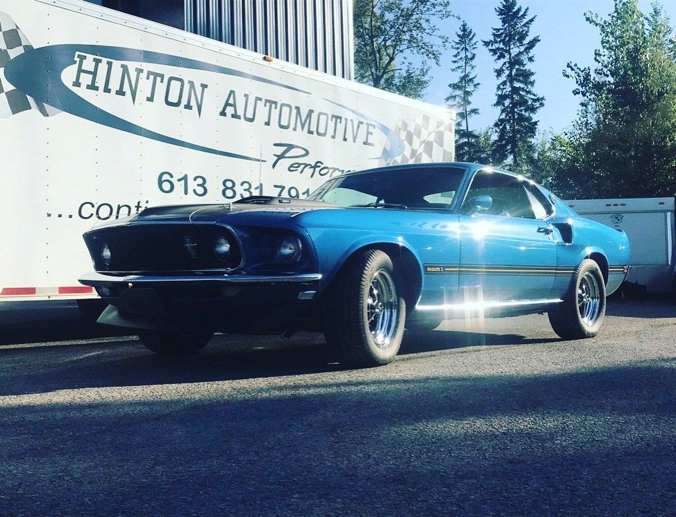 A blue car is parked in front of a hinton automotive truck