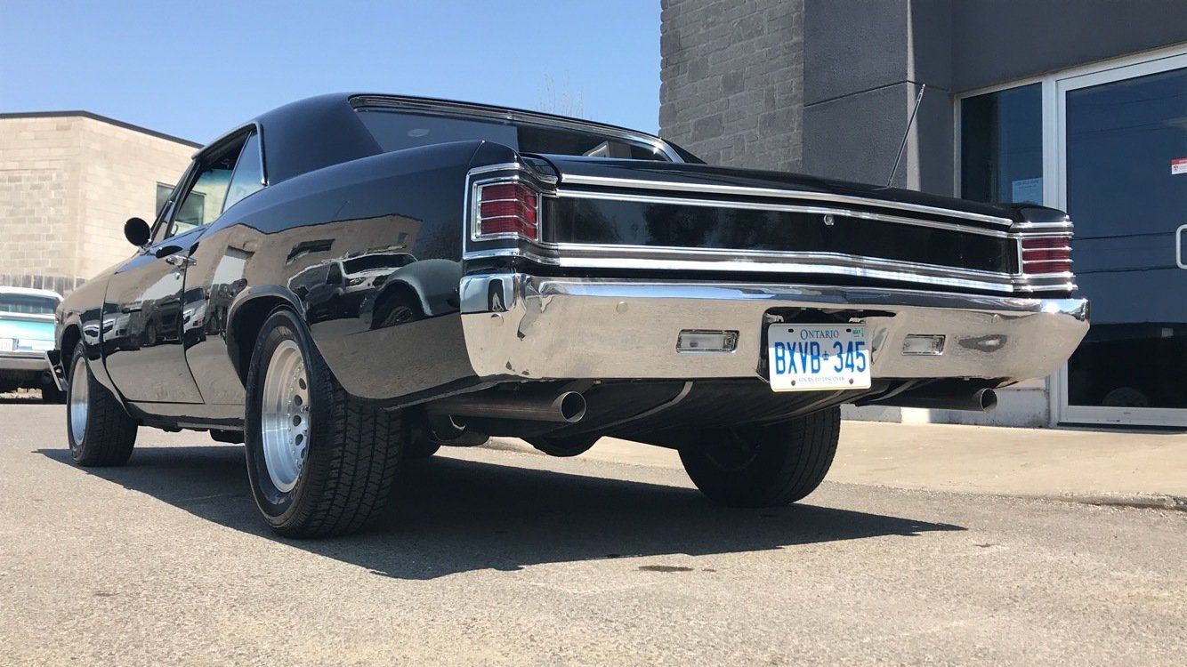 A black car is parked in front of a building with a license plate that says eoy-303