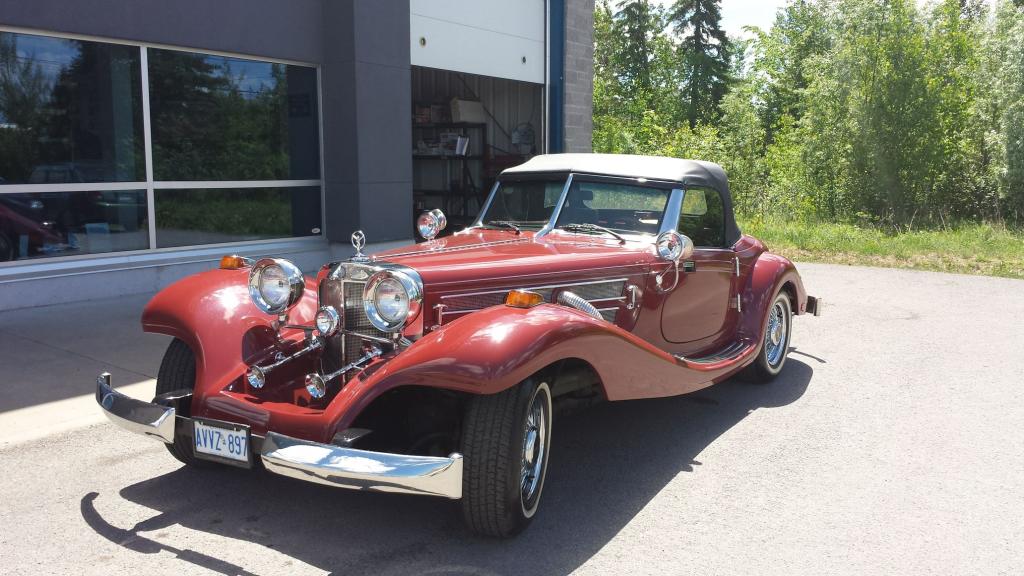 A red vintage car is parked in front of a building