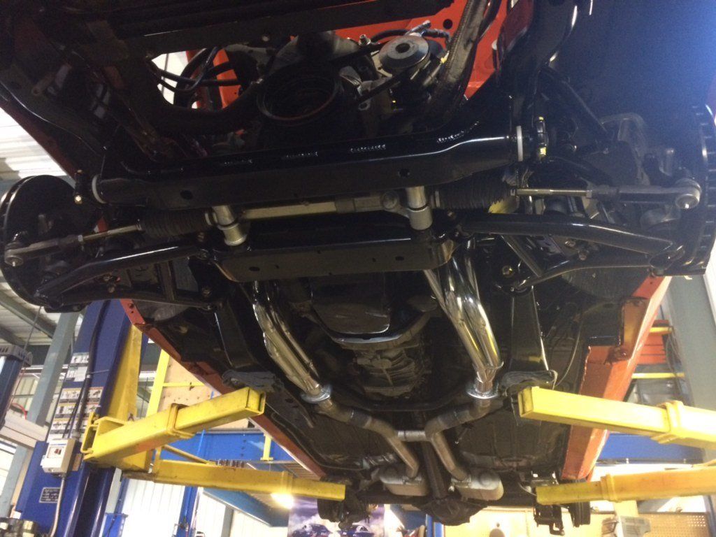 The underside of a car on a lift in a garage