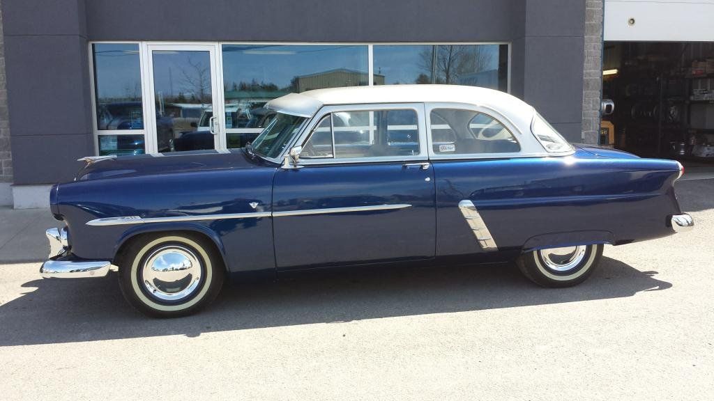 A blue and white car is parked in front of a building.